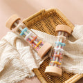 Wooden Montessori rainmaker rattle with colorful beads in woven basket display.