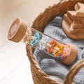 Wooden Montessori rainmaker rattle with colorful beads in child's hands, close-up view.