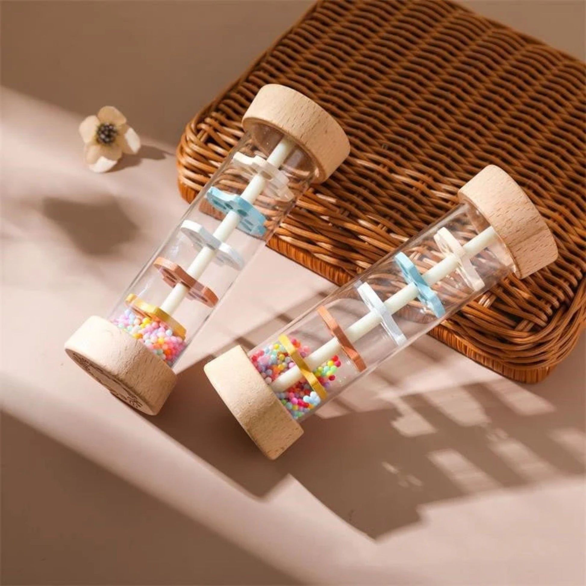 Montessori wooden rainmaker rattles with colorful beads on wicker basket