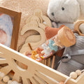 Montessori wooden rainmaker rattle with colorful beads in neutral nursery setting.