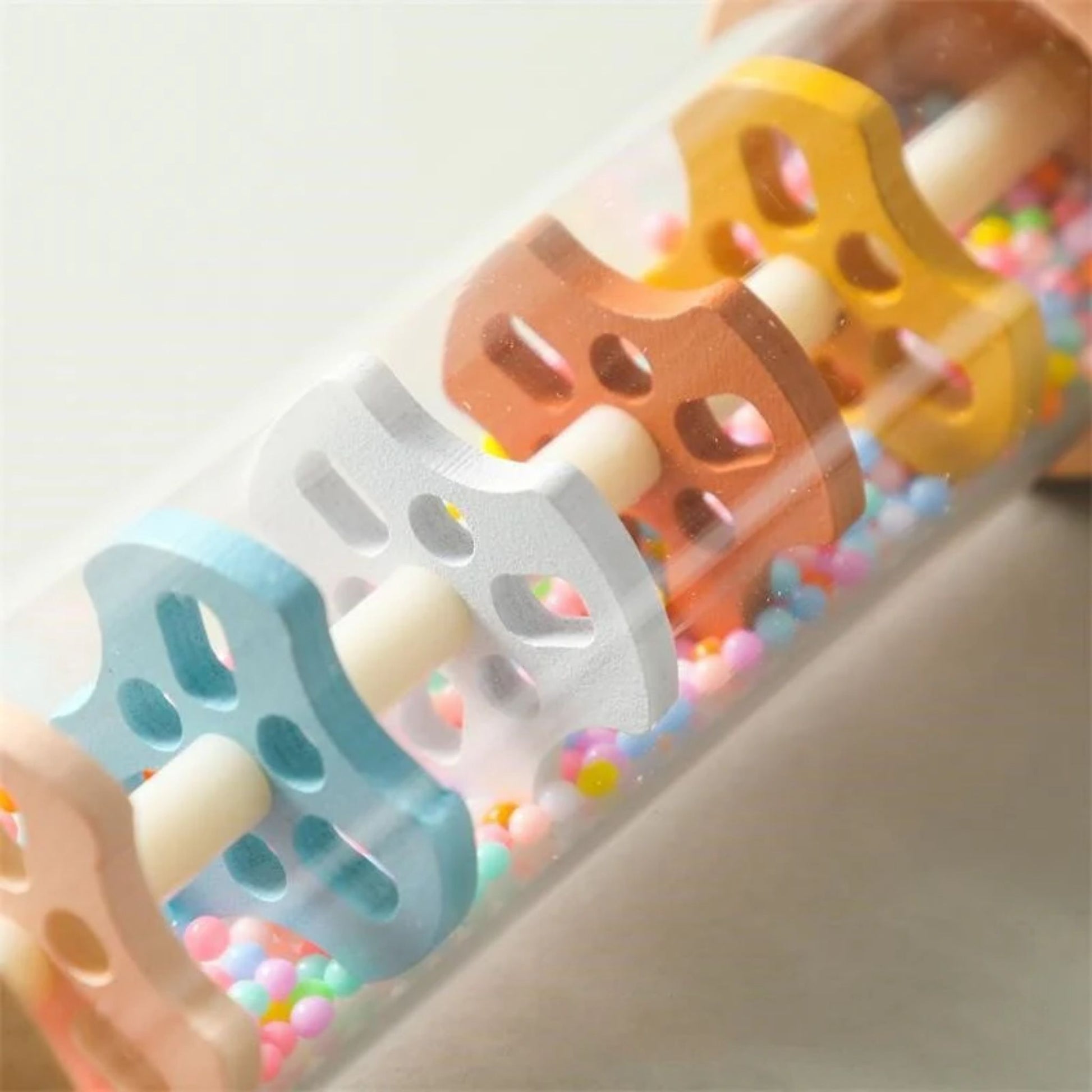 Montessori wooden rainmaker rattles in assorted colors with colorful beads inside.