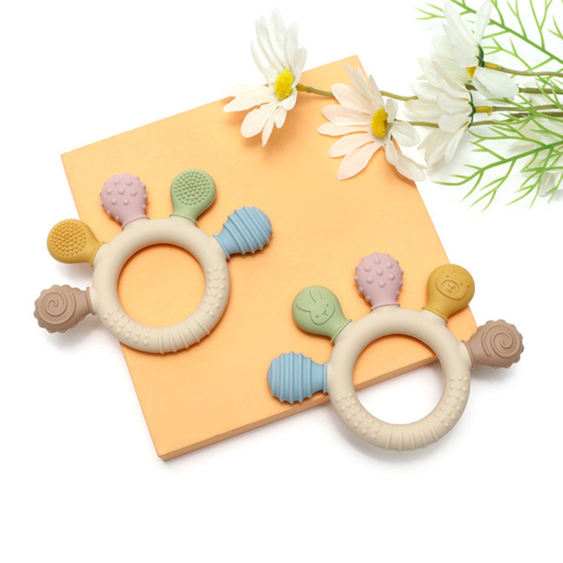 Montessori silicone teething rings with textured attachments in pastel colors on yellow background