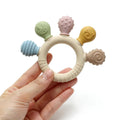 Montessori silicone teething ring with five textured attachments held in hand.