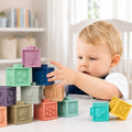 Toddler reaching for a stack of pastel Montessori squeaky building blocks with embossed animals and numbers.